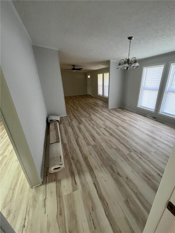 unfurnished living room with a textured ceiling, wood finished floors, and a chandelier