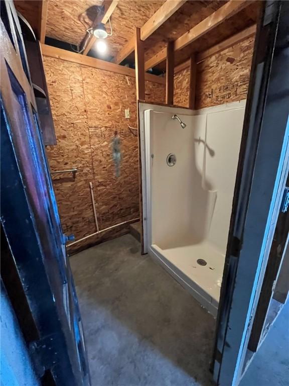 full bathroom featuring a shower stall and unfinished concrete floors