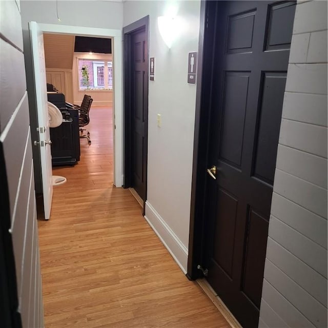 corridor with baseboards and light wood-style floors