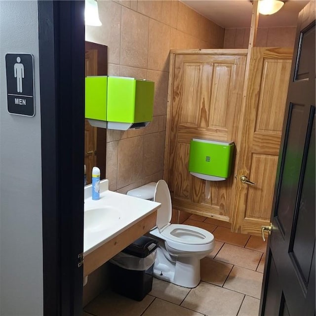 bathroom featuring tile patterned floors, toilet, and tile walls