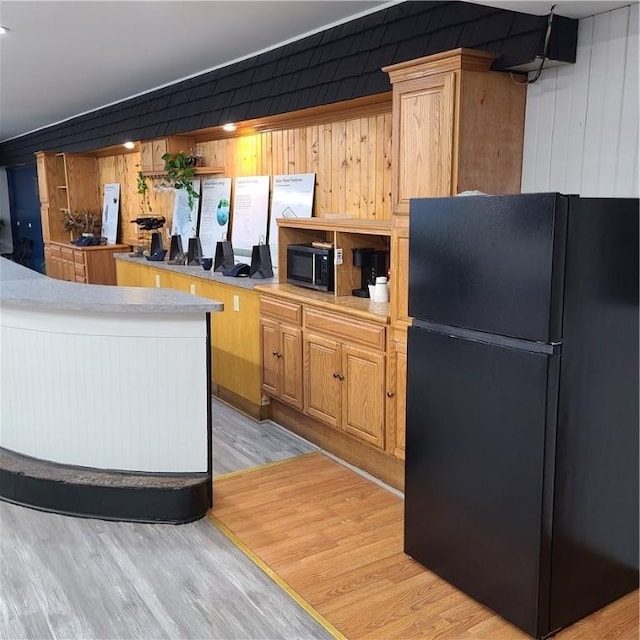 kitchen featuring black appliances, light wood-type flooring, and light countertops