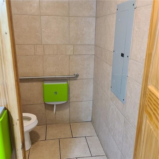 bathroom featuring electric panel, toilet, tile walls, and tile patterned flooring