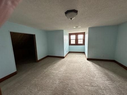 carpeted empty room featuring a textured ceiling and baseboards