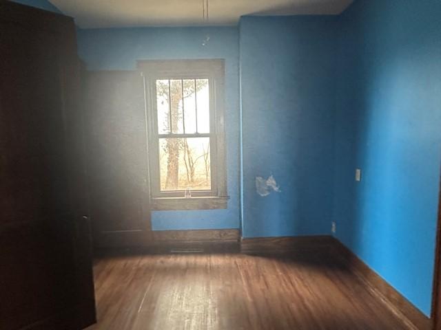 unfurnished room with baseboards and wood finished floors