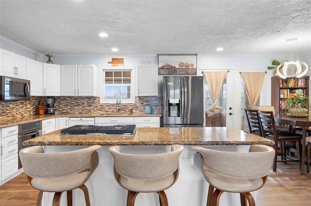 kitchen with a kitchen bar, a sink, stainless steel appliances, and light wood finished floors