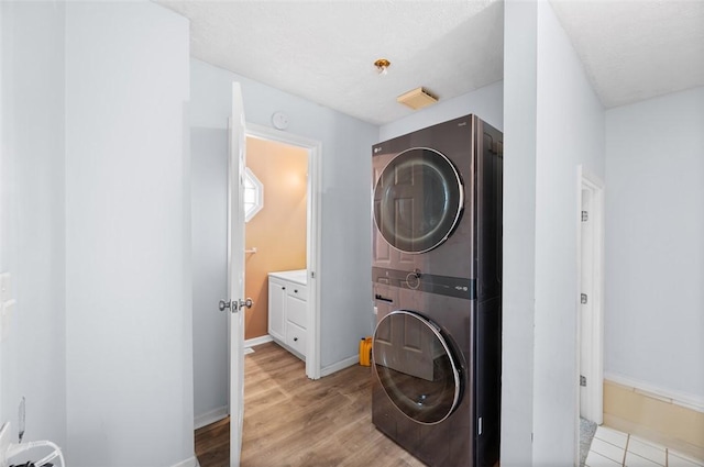 laundry room with baseboards, light wood-style floors, stacked washer / dryer, and laundry area