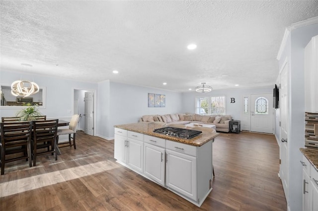 kitchen featuring open floor plan, white cabinets, wood finished floors, and a chandelier
