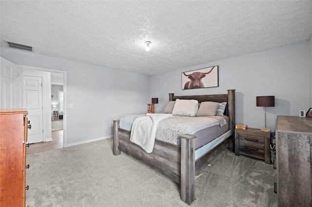 carpeted bedroom featuring baseboards, visible vents, and a textured ceiling