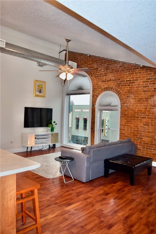 living room with ceiling fan, brick wall, lofted ceiling, and wood-type flooring