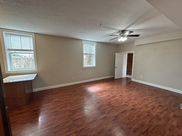 empty room featuring a textured ceiling, ceiling fan, and dark wood-type flooring