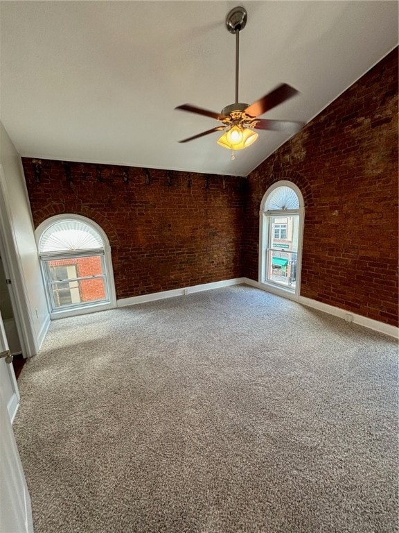 unfurnished room with ceiling fan, plenty of natural light, and brick wall