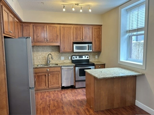 kitchen featuring decorative backsplash, light stone counters, dark wood-type flooring, and appliances with stainless steel finishes