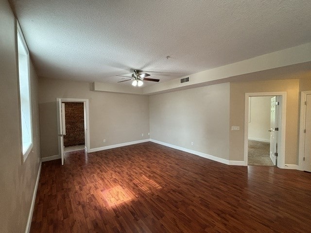 unfurnished room with a textured ceiling, ceiling fan, and dark wood-type flooring