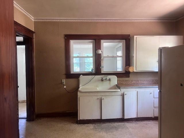 113 S 25th St, Mattoon, IL 61938 - kitchen with freestanding refrigerator, white cabinetry, crown molding, and light countertops