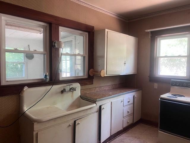 113 S 25th St, Mattoon, IL 61938 - kitchen with white range with electric cooktop, white cabinets, crown molding, and light tile patterned floors