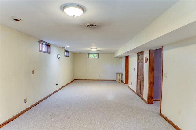 basement with baseboards, visible vents, and light carpet
