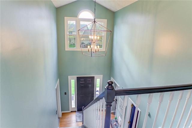 foyer featuring high vaulted ceiling, stairs, wood finished floors, and a notable chandelier