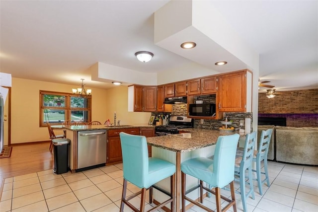 1230 Finley Ave, Mt Zion, IL 62549 - kitchen featuring appliances with stainless steel finishes, a peninsula, a ceiling fan, a chandelier, and dark stone counters