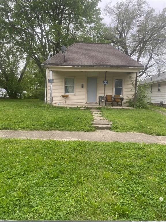 bungalow-style house with a shingled roof and a front lawn