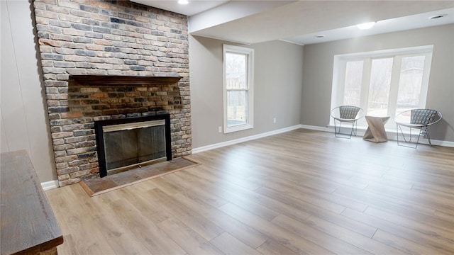 unfurnished living room with baseboards, wood finished floors, and a fireplace