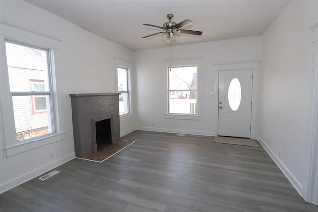 entrance foyer featuring visible vents, a ceiling fan, dark wood-style floors, a fireplace, and baseboards