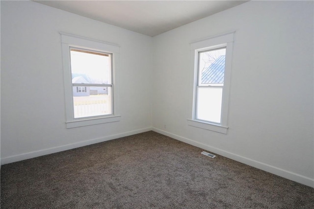 carpeted spare room featuring visible vents and baseboards