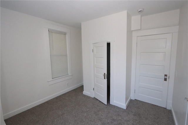 unfurnished bedroom featuring baseboards and dark carpet