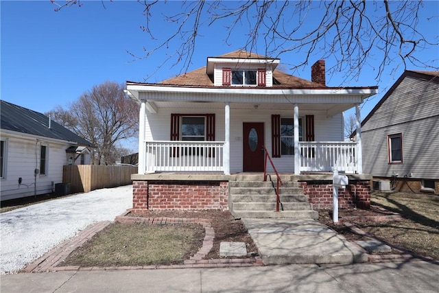 bungalow-style home with a porch, central AC unit, and fence