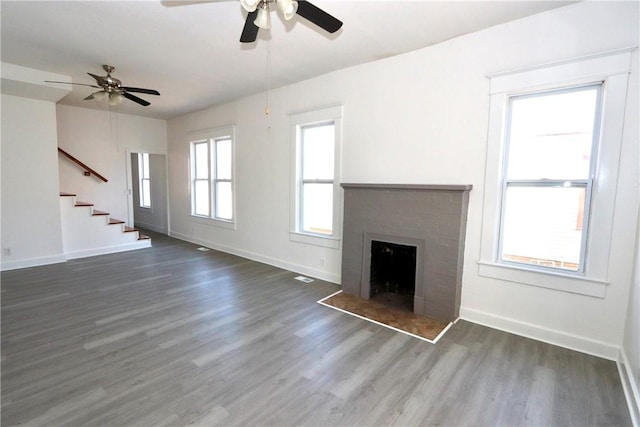 unfurnished living room featuring stairs, wood finished floors, baseboards, and a fireplace