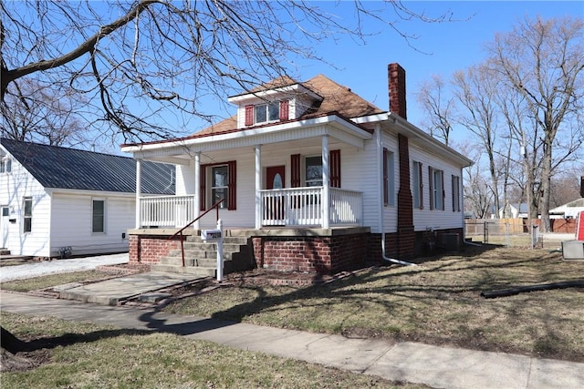 view of front of property with a porch, a chimney, and fence