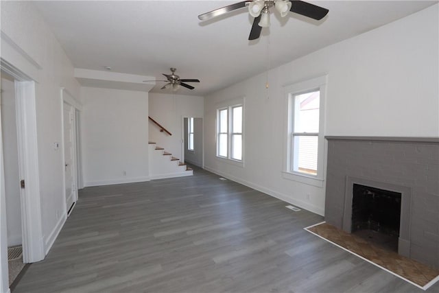 unfurnished living room with wood finished floors, visible vents, baseboards, a fireplace, and stairs