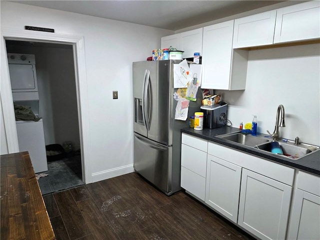 403 11th St, Georgetown, IL 61846 - kitchen featuring a sink, dark wood finished floors, dark countertops, white cabinets, and stacked washer / dryer