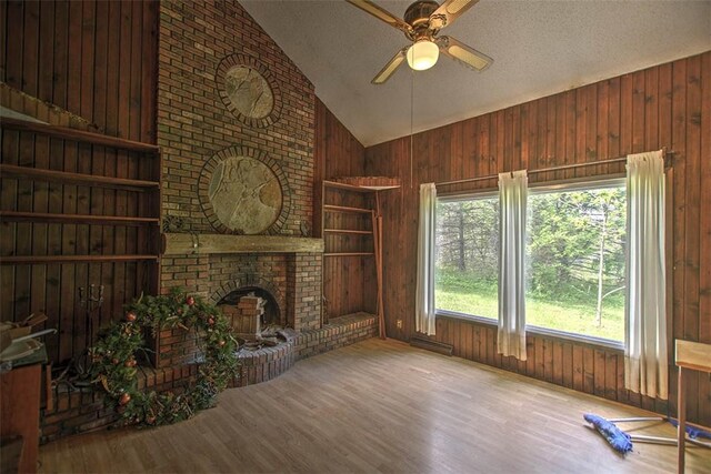 2752 N Sangamon Rd, Decatur, IL 62521 - unfurnished living room featuring wooden walls, wood finished floors, ceiling fan, a fireplace, and a textured ceiling
