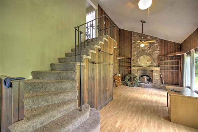 2752 N Sangamon Rd, Decatur, IL 62521 - stairs featuring ceiling fan, wooden walls, high vaulted ceiling, wood finished floors, and a fireplace