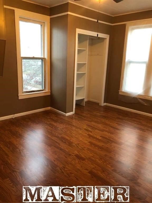 unfurnished bedroom with dark hardwood / wood-style floors, ornamental molding, and a closet