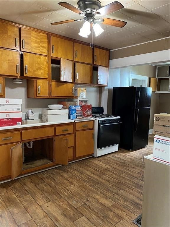 kitchen featuring wood-type flooring, black fridge, white gas range, and ceiling fan