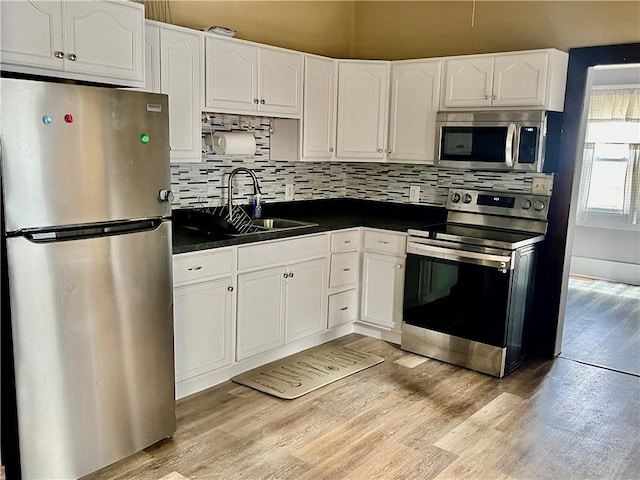 kitchen featuring sink, white cabinets, light wood-type flooring, and appliances with stainless steel finishes