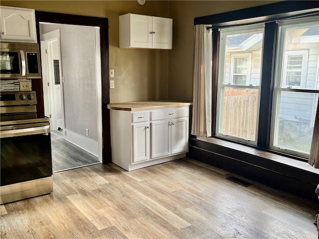 kitchen featuring white cabinets, a wealth of natural light, light hardwood / wood-style floors, and appliances with stainless steel finishes