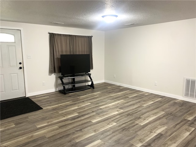 unfurnished living room featuring dark wood-type flooring and a textured ceiling