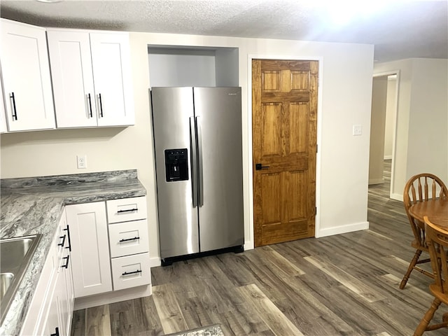 kitchen featuring white cabinetry, sink, stainless steel fridge, dark wood-type flooring, and a textured ceiling