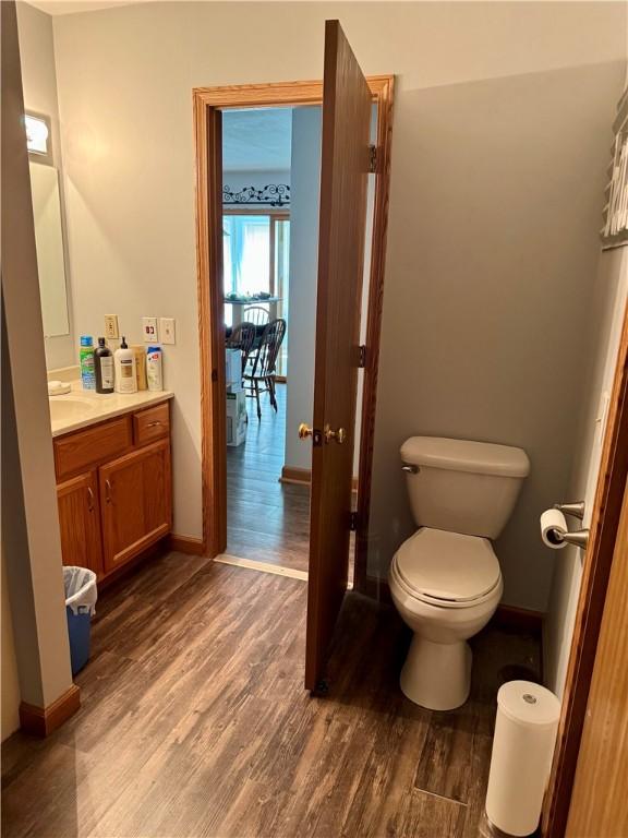 bathroom featuring vanity, toilet, wood finished floors, and baseboards
