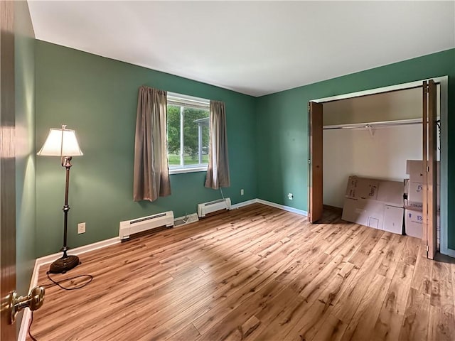 2145 E 1500 N Rd, Shelbyville, IL 62565 - unfurnished bedroom with baseboard heating, wood finished floors, and baseboards