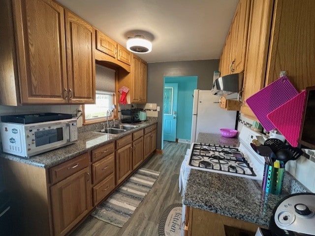 kitchen with sink, ventilation hood, white refrigerator, dark hardwood / wood-style floors, and dark stone counters