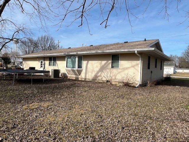 back of property with central AC unit and a trampoline