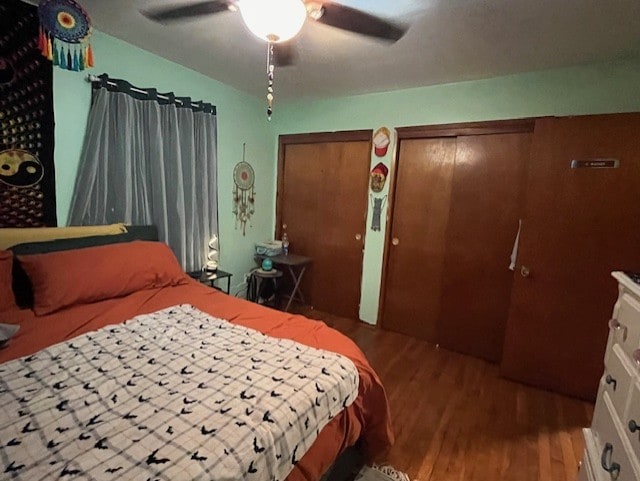 bedroom with ceiling fan, hardwood / wood-style flooring, and multiple closets