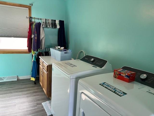 clothes washing area featuring cabinets, dark wood-type flooring, and independent washer and dryer