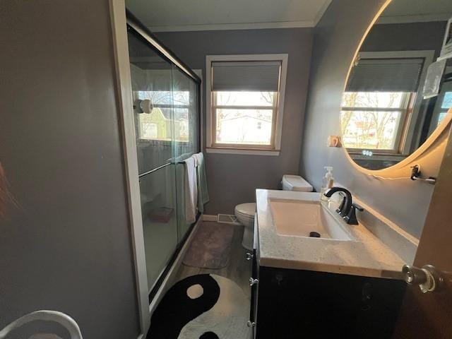 bathroom featuring crown molding, vanity, toilet, and an enclosed shower