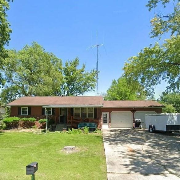 single story home with an attached garage, a porch, concrete driveway, and a front lawn