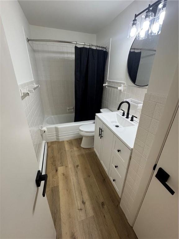 2631 Gregory Ct, Decatur, IL 62526 - bathroom with tile walls, wood finished floors, vanity, baseboard heating, and shower / bath combo with shower curtain