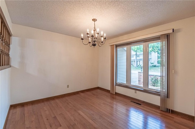 4642 Dogwood Ct, Decatur, IL 62526 - unfurnished room with a chandelier, light wood finished floors, and a textured ceiling